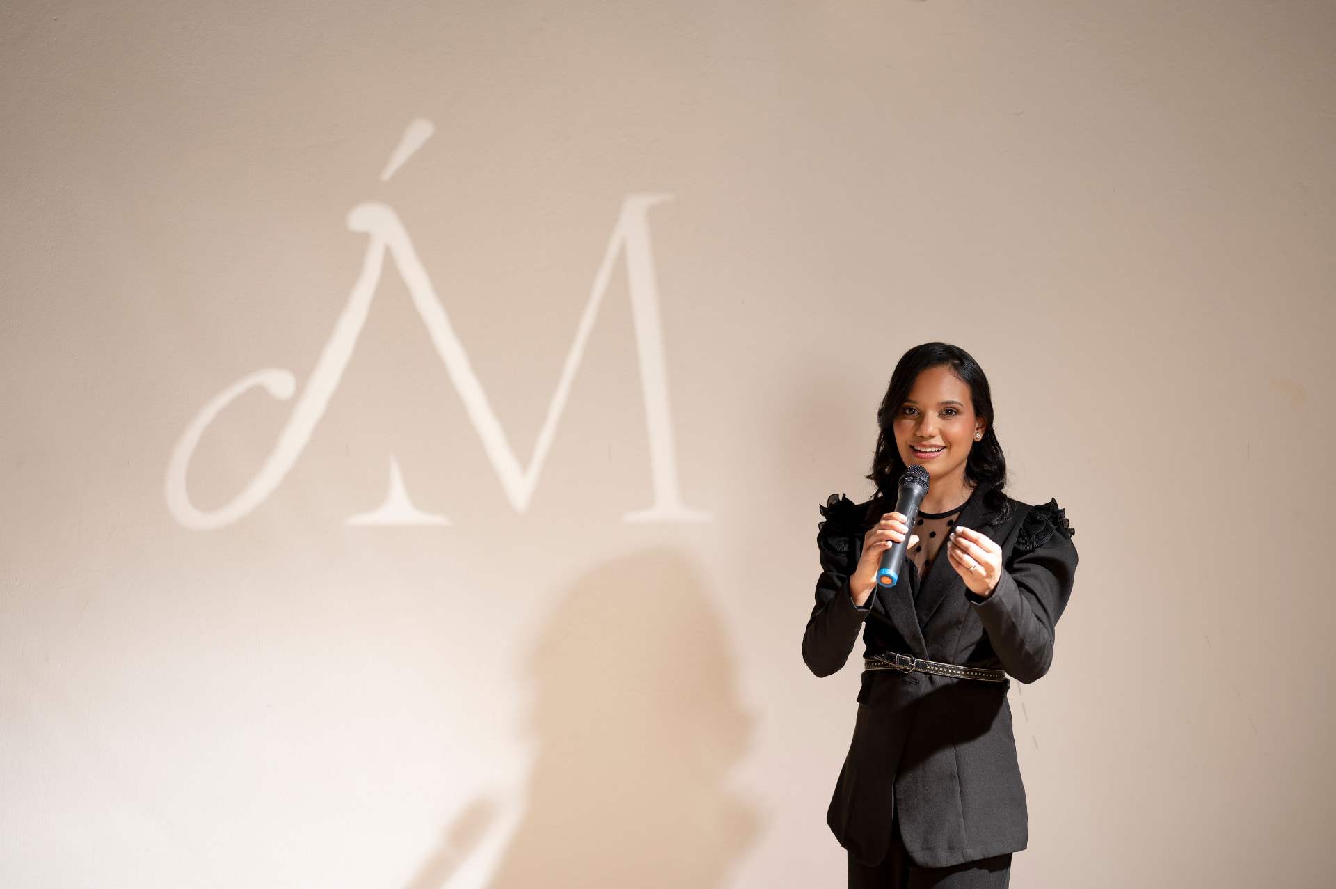 Jeniffer Mora durante una presentación con su logo al fondo